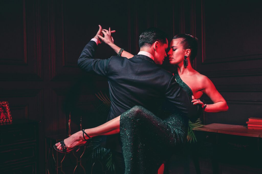 A couple elegantly dancing with intense passion under red lighting, showcasing intimacy and glamour.